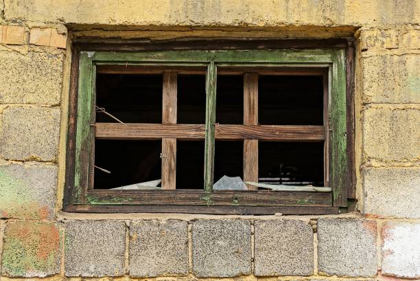 istock a small window with broken pieces of glass on a brick wall 893078818