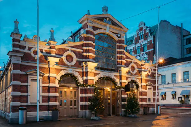 Helsinki, Finland. Old Market Hall Vanha Kauppahalli In Lighting At Evening Or Night Illumination. Famous Popular Place In  Christmas Holiday Season