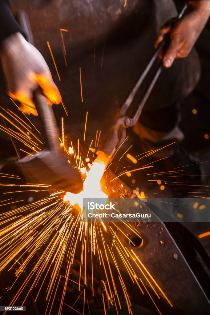 Knife Maker Shaping Hot Piece Of Iron on Anvil With Hammer Blacksmith Stock Photo