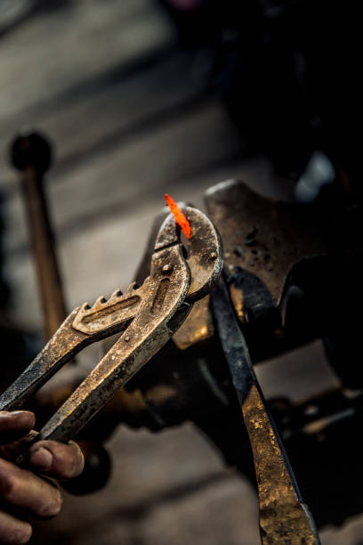 istock Blacksmith Shaping Metal Head Of Ram Using The Forge Tongs 893102678