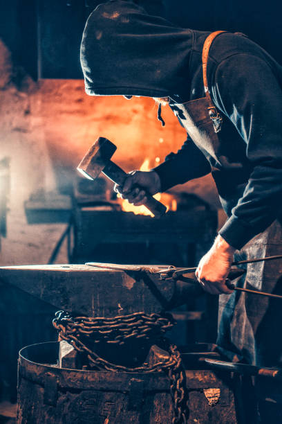 istock Young Blacksmith Shaping Glowing Knife Iron Blade On Anvil 893102752