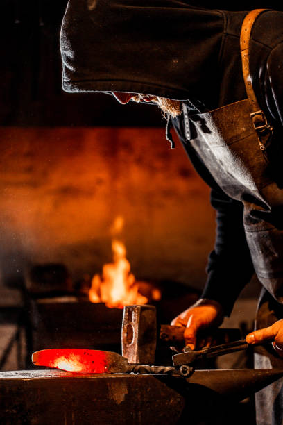 istock Young Blacksmith Shaping Glowing Knife Iron Blade On Anvil 893102760