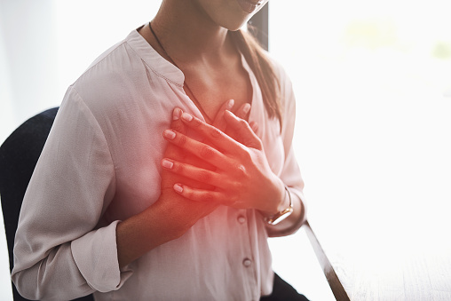 Closeup shot of an unidentifiable businesswoman holding her chest in pain