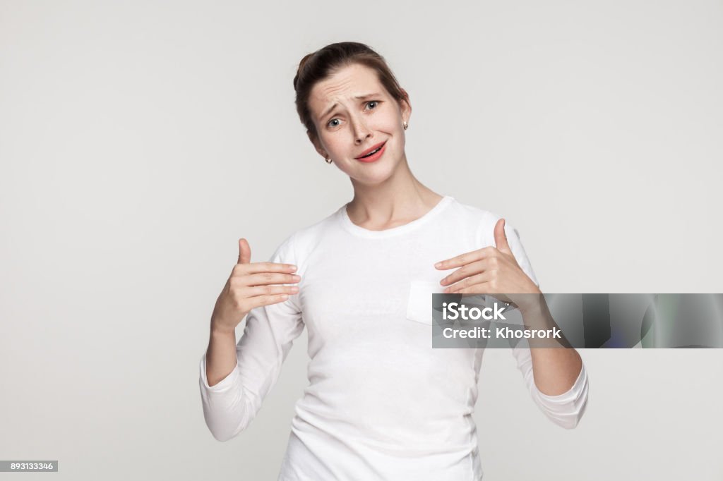 Puffy funny woman pointing hands himself and looking at camera. Puffy funny woman pointing hands himself and looking at camera. Studio shot, gray background Actor Stock Photo