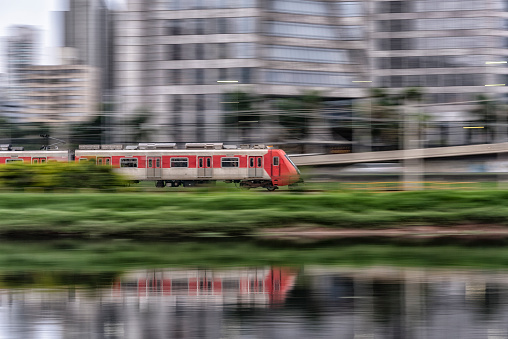 Fast moving urban red train with reflection in the river, São Paulo, Brazil