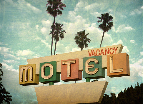 aged and worn neon motel sign with palm trees