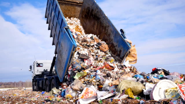 Garbage truck disposed trash on the landfill. Vehicle transporting garbage to waste.