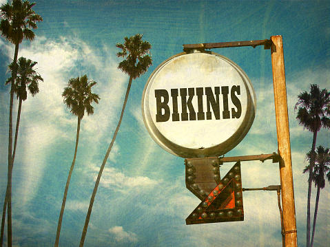 aged and worn bikinis sign with palm trees
