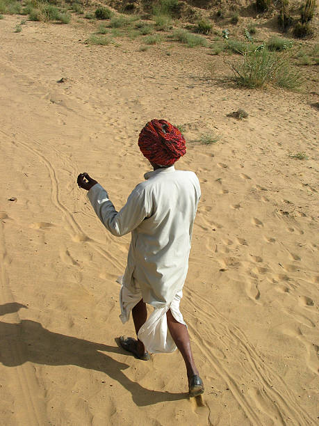 Udaipur, India - December 29, 2022 : Unidentified old aged Rajasthani man in traditional attire smoking using old fashioned method
