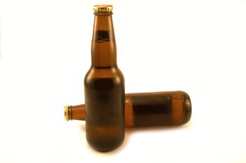 horizontal color photograph of a large group of amber colored beer bottles against a white background