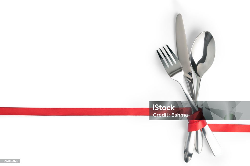 Fork, spoon and knife tied with a red ribbon isolated with copy space Fork, spoon and knife tied with a red ribbon. Isolated on white, clipping path included. Food, restaurant and table setting theme template with copy space Lunch Stock Photo