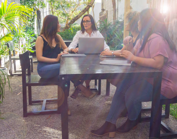 istock Four women in discussion around table in conservatory area 893186232