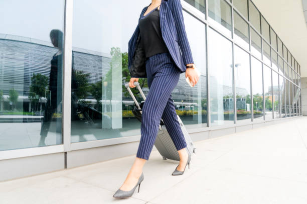 istock Businesswoman pulling wheeled suitcase outside airport 893190998