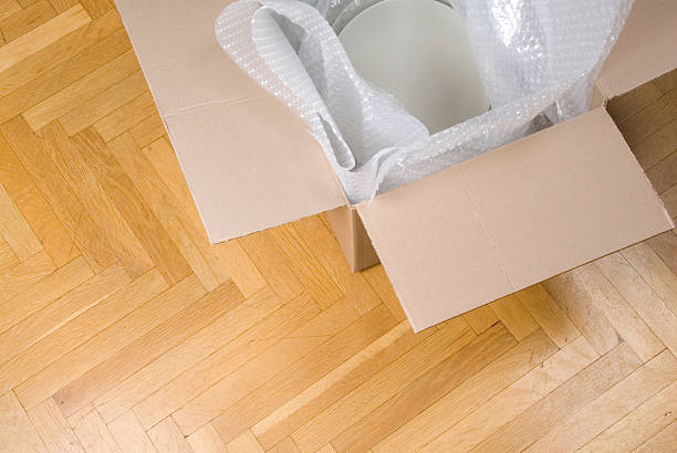 Packing plates with protective bubble wrap and cardboard box stock photo