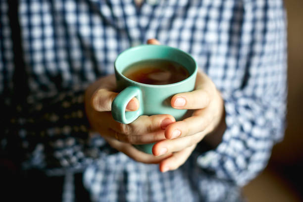 istock a young woman sits by the window and holds a mug with hot tea 893247152