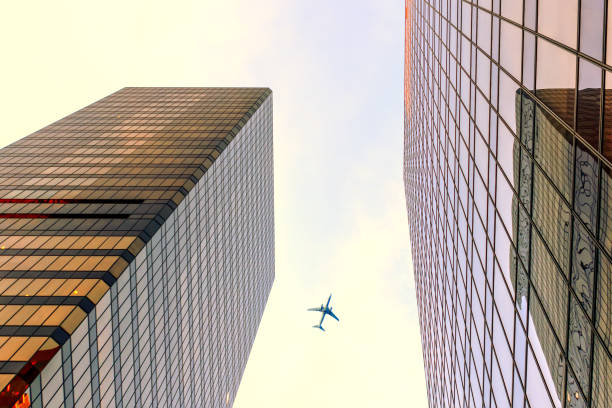 istock view from below upwards on glass modern skyscrapers and flying airplane 893267764