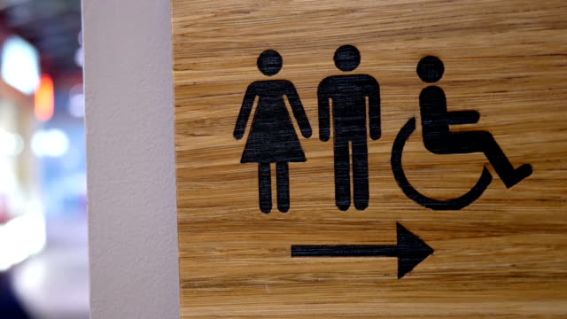 Motion of wooden man and woman washroom logo on wall inside Burnaby shopping mall
