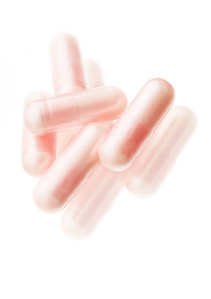 розовый сияющий таблетки - vitamin pill vertical high key photographic effects стоковые фото и изображения
