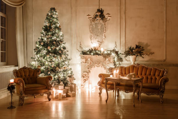 istock classical interior of a white room with a decorated fireplace, sofa, Christmas tree, garlands, candles,lanterns, gifts in the evening 893285692