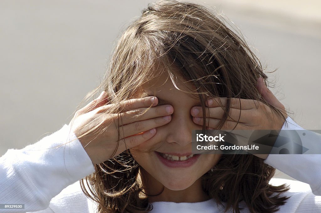 Menina com as mãos sobre os olhos e um sorriso - Foto de stock de Esconder royalty-free