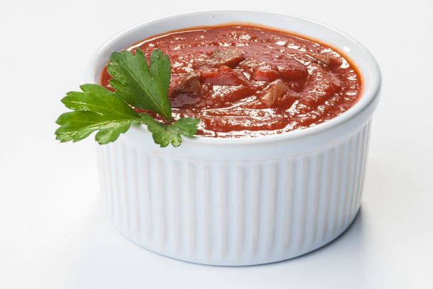 istock Fresh red tomato salsa in white bowl with mint and parsley on white background 893320972