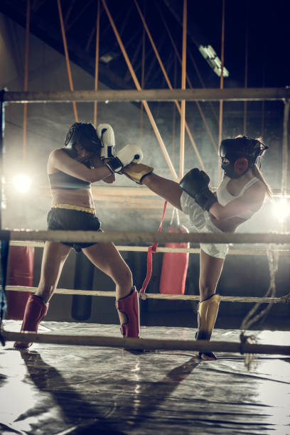 istock Two athletic women fighting on a kickboxing match in a gym. 893341414