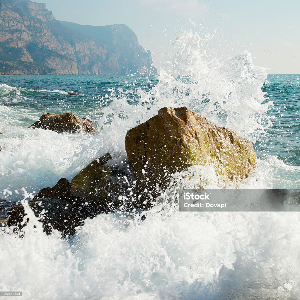 Waves in the sea breaking on a rock in the sea  Storm. Waves and sea foam. Rock - Object Stock Photo