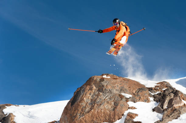 istock A professional skier makes a jump-drop from a high cliff against a blue sky leaving a trail of snow powder in the mountains 893348154