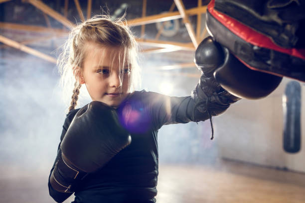 Small boxer exercising punches on a sports training in a gym. Little girl having a boxing training in a health club. kickboxing photos stock pictures, royalty-free photos & images