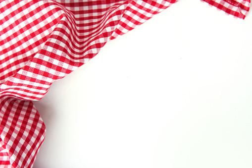 Red checkered gingham kitchen towel over white table empty space background. Picnic clothes decoration.