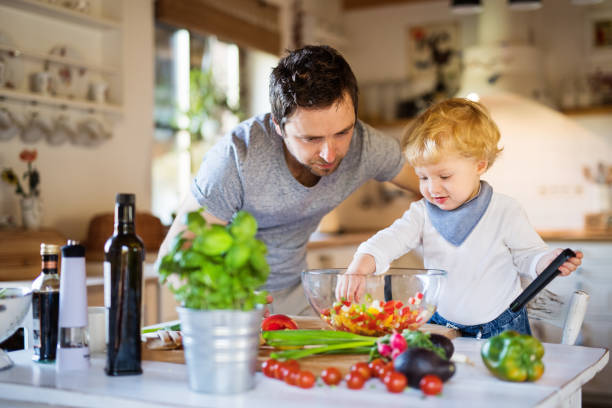 istock Young father with a toddler boy cooking. 893385550