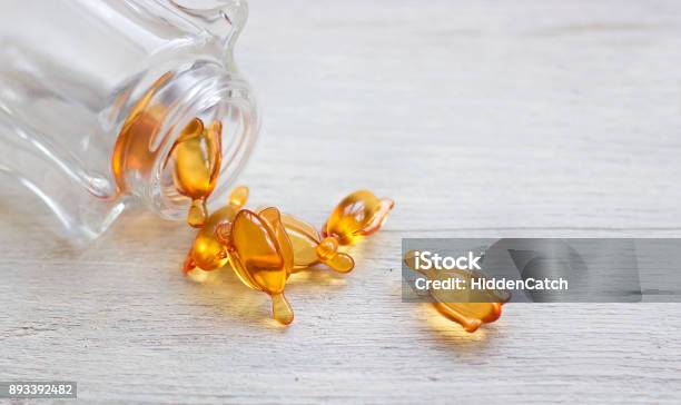 Skin And Hair Vitamin Serum Orange Capsules On White Table Stock Photo - Download Image Now