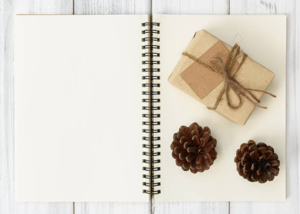 istock Notebook,pine cone and brown parcel gift box on white wood table background 893392800