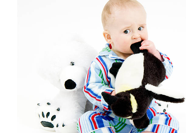 istock Infant in pajamas chewing on stuffed penguin 89340056