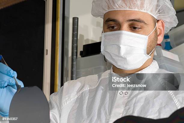 Un Uomo In Una Maschera E Di Cap Lavorando A Wafer Di Silicio - Fotografie stock e altre immagini di Laboratorio