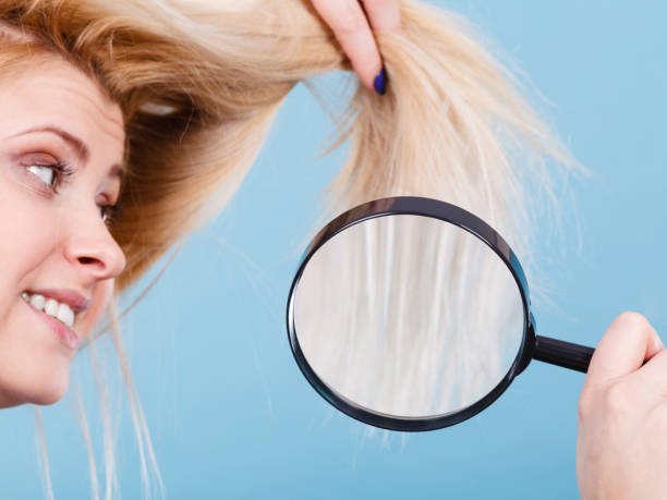 istock Woman looking at hair through magnifying glass 893407586