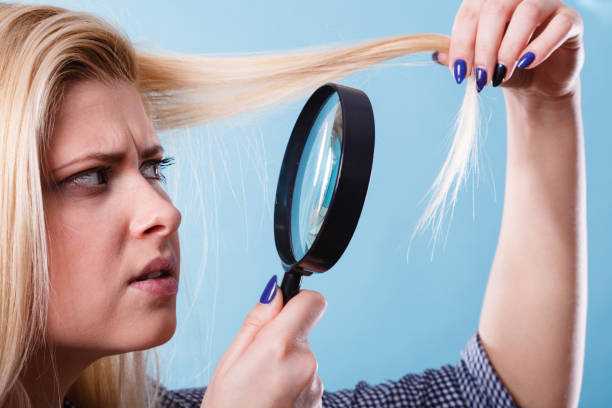 istock Woman looking at hair through magnifying glass 893407714