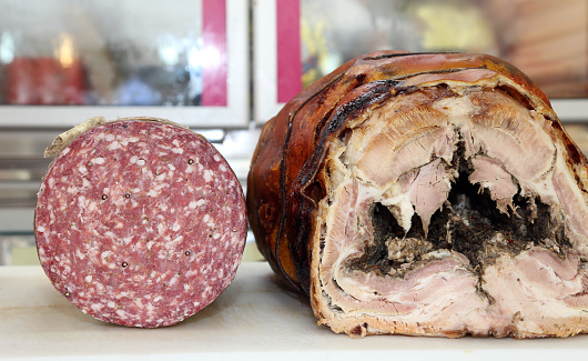 two typical Italian salami Soppressa and porchetta that is cooked pork for sale at the delicatessen