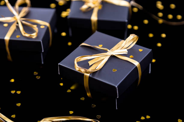 istock Black gift boxes with gold ribbon on shine background. Close up. 893419666