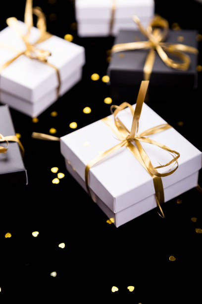 istock Black and white gift boxes with gold ribbon on shine background. Close up. 893419688
