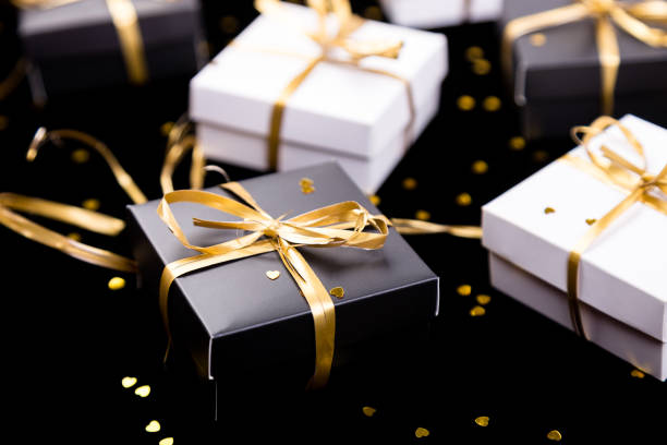 istock Black and white gift boxes with gold ribbon on shine background. Close up. 893419700
