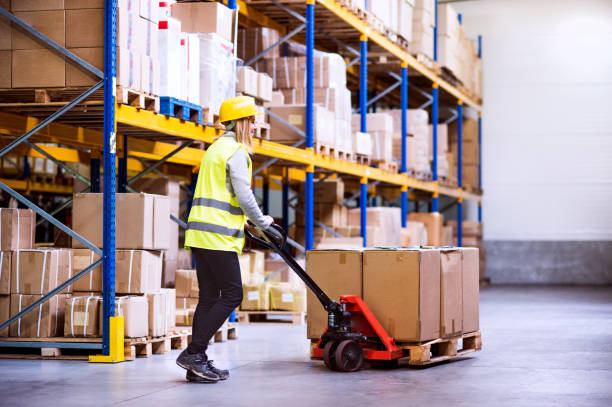 istock Woman warehouse worker with hand forklift truck. 893420188