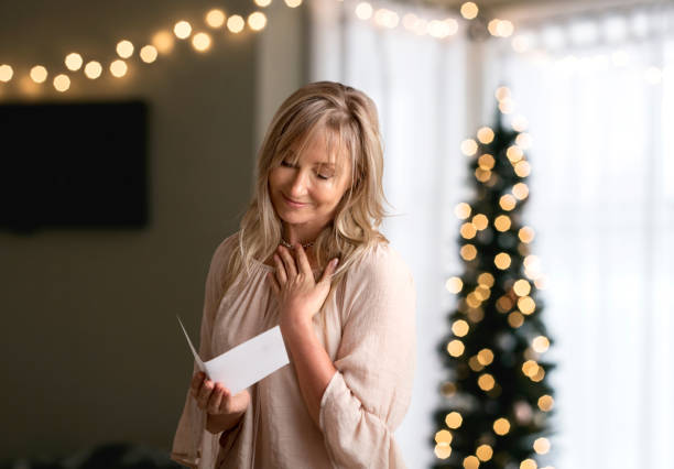 Woman reading a heartfelt message in a card at Christmas time stock photo