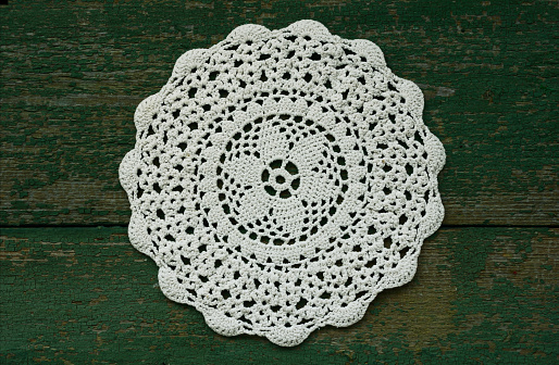 Snowflake like vintage crocheted lace napkin with copy space on rusted wooden background