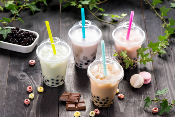 Variety of bubble tea in plastic cups with straws on a wooden table. Variety of bubble tea in plastic cups with straws on a wooden table. tea with milk stock pictures, royalty-free photos & images