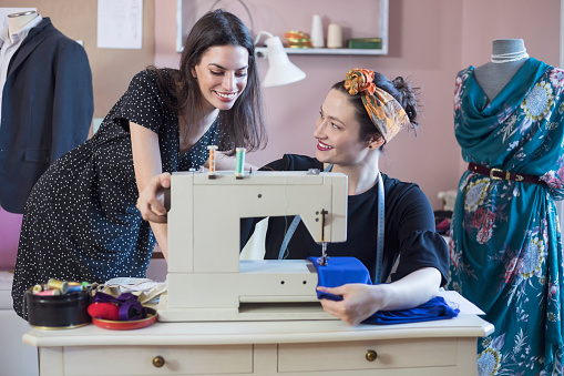 Young woman visiting her dressmaker in tailor workshop