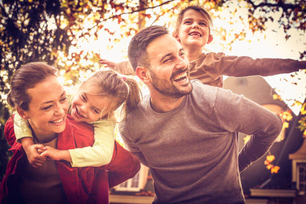 padres llevar a niñas en piggyback. tiempo en familia. - family white family with two children cheerful fotografías e imágenes de stock