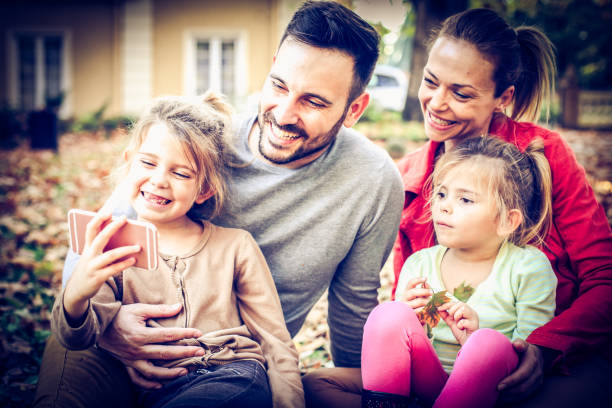 obtener sonrisa a cámara, niña tomar una foto de familia todos. en el exterior. - two parent family technology mobility men fotografías e imágenes de stock