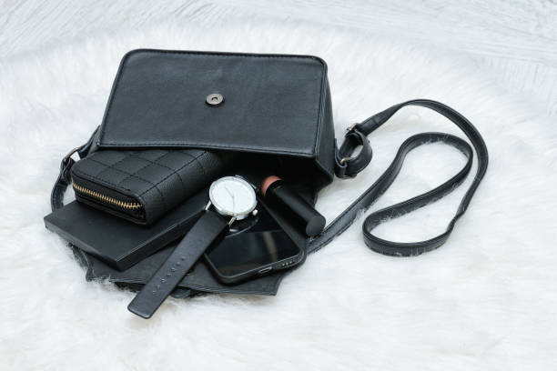 istock Open black bag with dropped things, notebook, mobile phone, watch and purse. Fur on background. Fashion concept 893459042