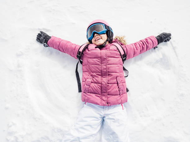 niña riendo y jugando a angel de nieve - snow gear fotografías e imágenes de stock